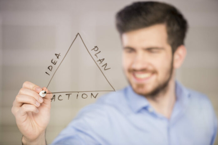 Young handsome businessman drawing on glass screen.