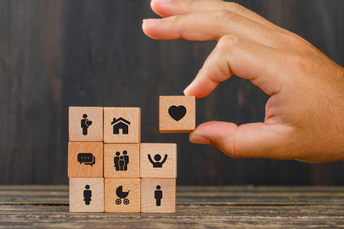 Relationship concept on wooden background side view hand holding wooden cube with heart icon