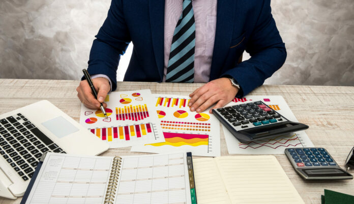 ispettore-finanziario-che-fa-rapporto-rapporto-di-pianificazione-finanziaria-utilizzando-carta-grafica-e-laptop-per-reddito-o-budget-di-vendita-quest-anno