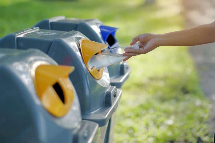 close-up-hand-putting-bottle-garbage-bin