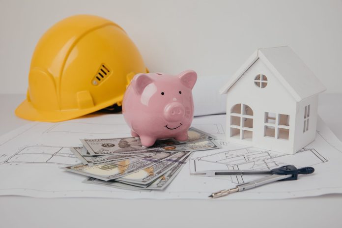 elmetto-giallo-e-salvadanaio-con-disegni-sul-tavolo-dell-ingegnere