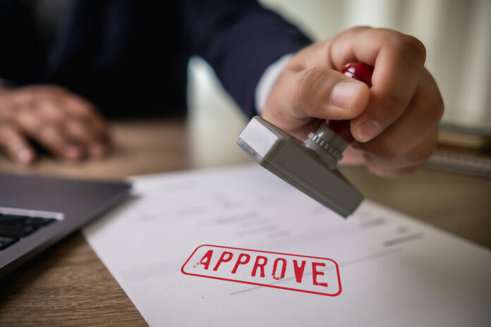 man stamping approval Text is approved by stamping the document